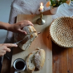 Zdjęcie przedstawia krojenie chleba. 