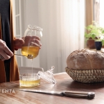 Zdjęcie przedstawia stół na którym jest kosz na chleb, świeżo upieczony chleb oraz miód.